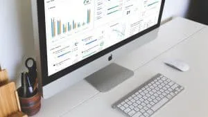 Monitor de computador exibindo gráficos diversos de métricas ágeis para scrum em uma mesa de escritório branca e minimalista